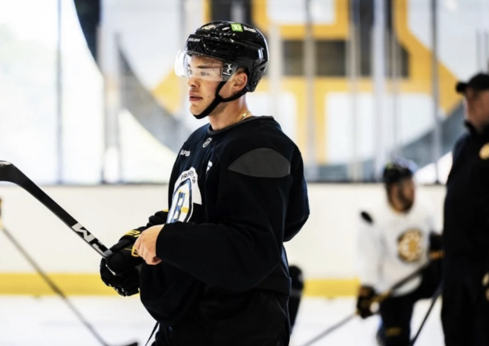 A hockey player in a Bruins uniform stands on the ice.
